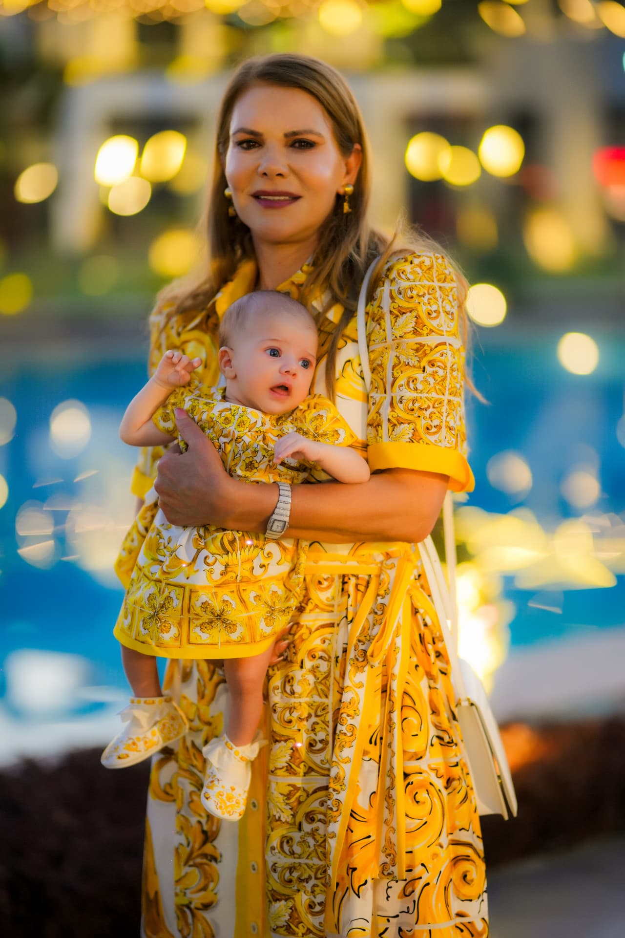 Grandmother in a yellow print dress holding her baby granddaughter