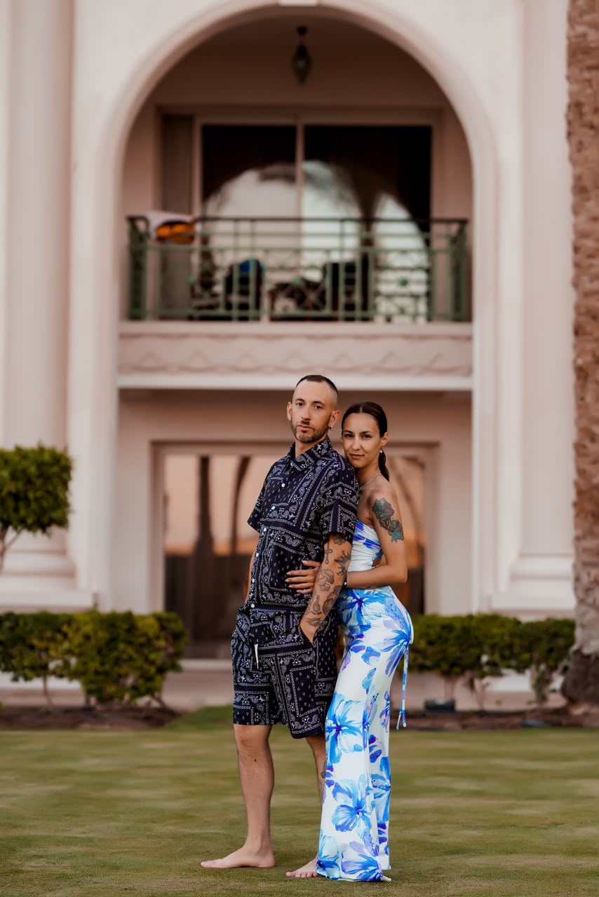 Couple posing in front of a white arched villa at golden hour