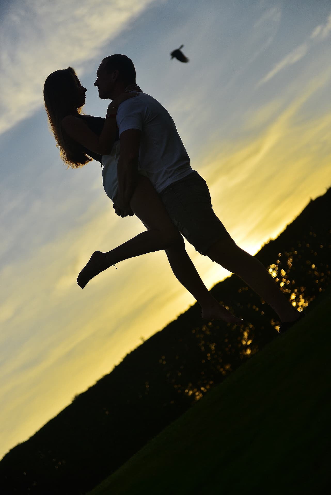 Silhouette of a man lifting his partner against a sunset sky