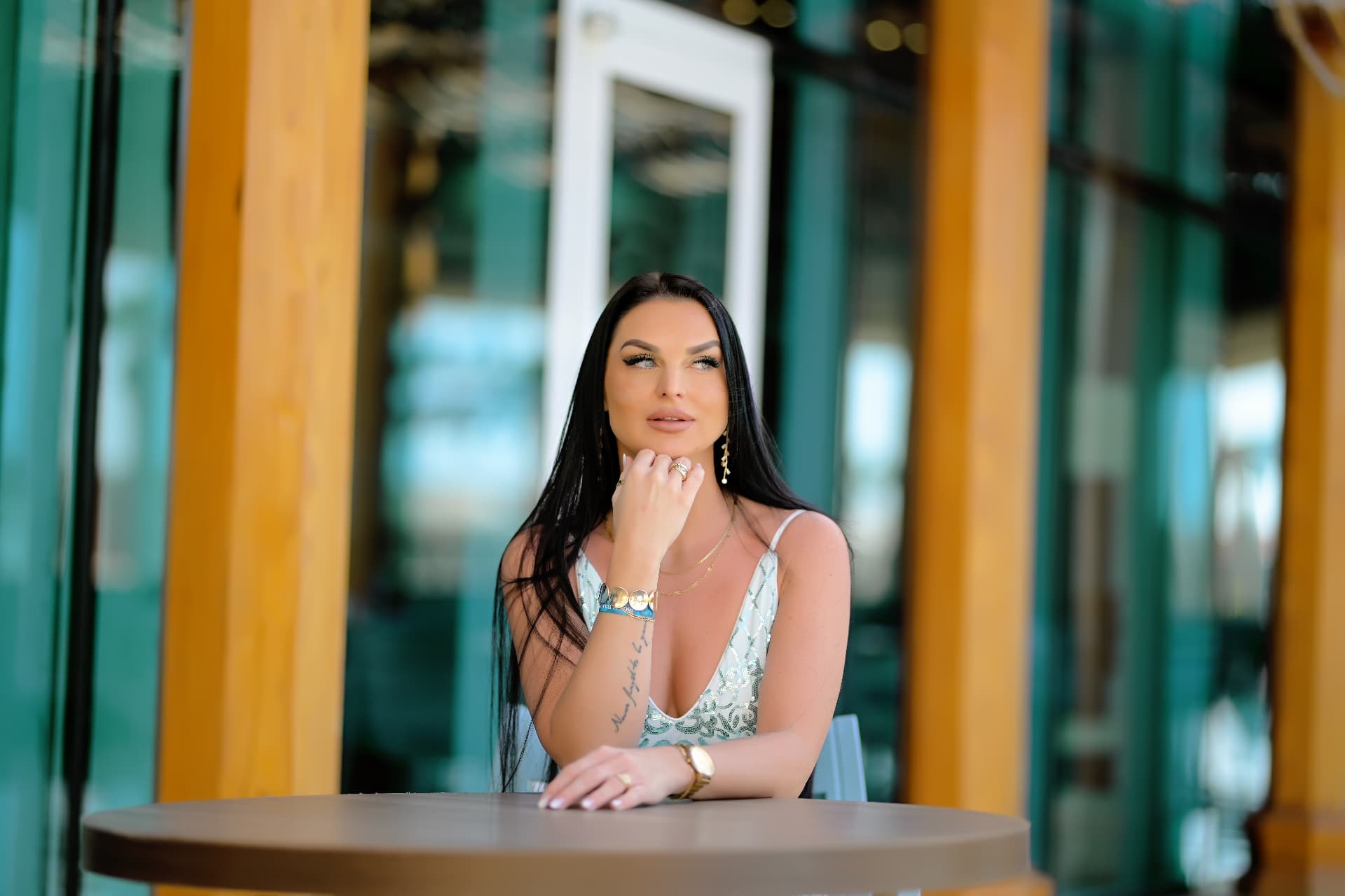 Woman in a sequin dress seated at a waterfront cafe table