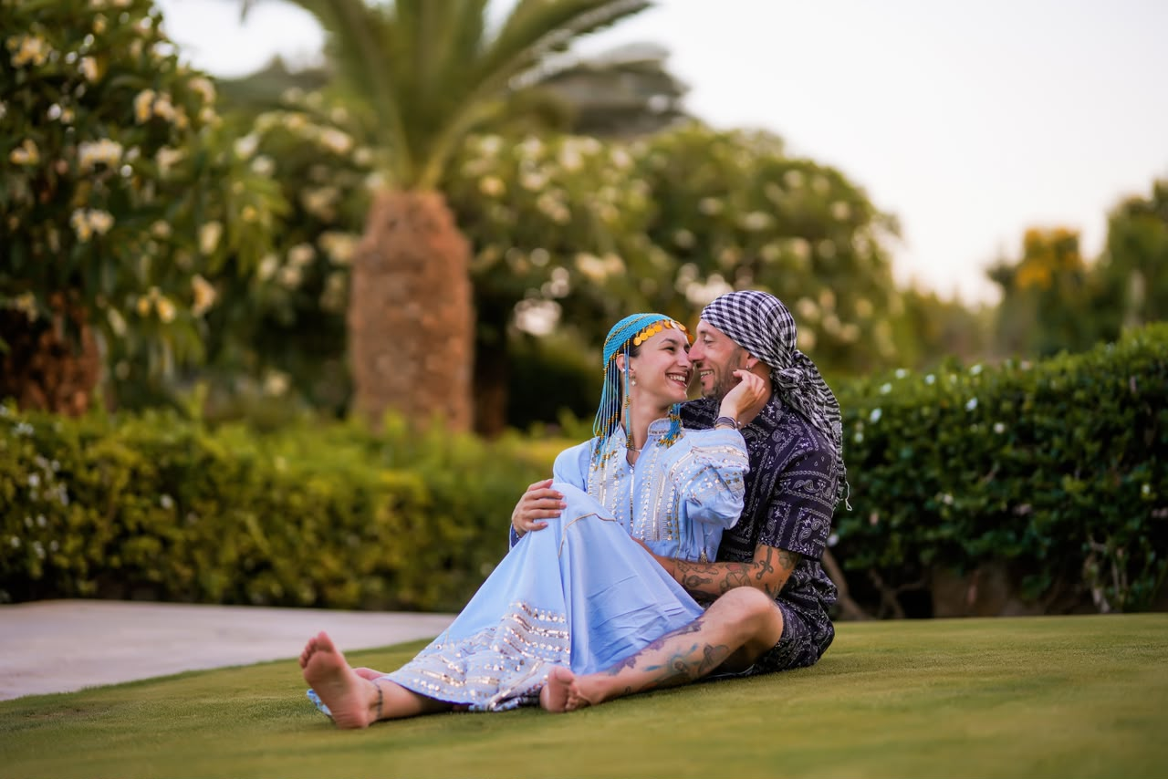 Couple in traditional dress sitting together on a lawn at dusk