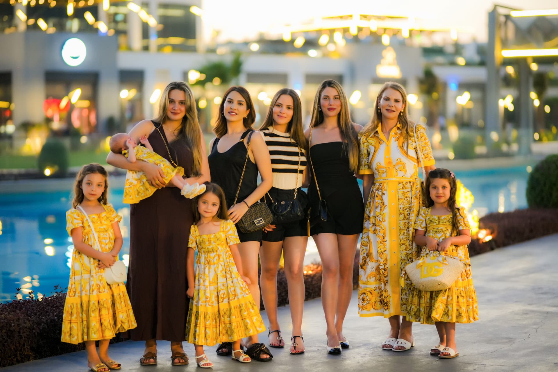Family group portrait of mothers, daughters and a newborn by the pool