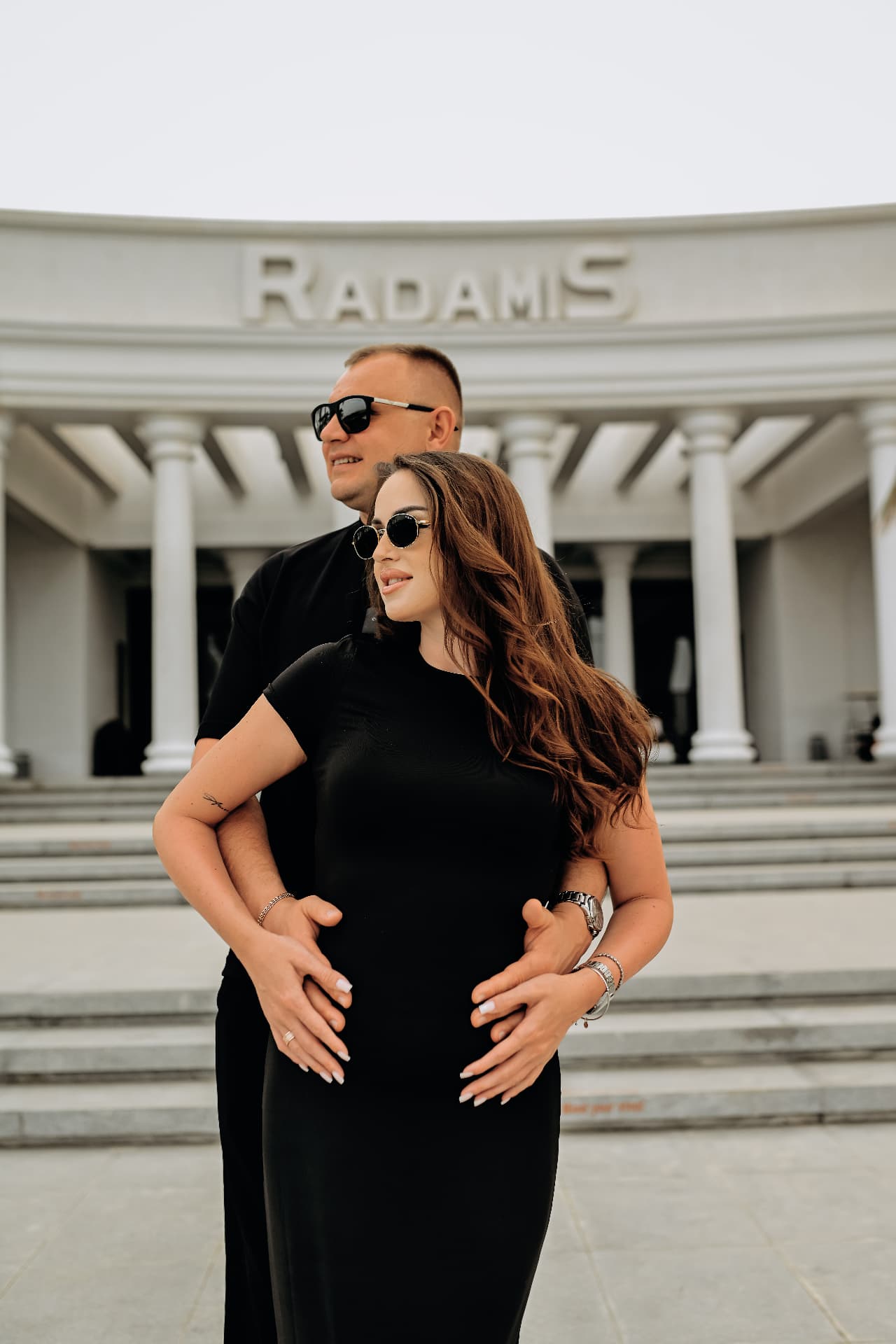 Couple in black posing in front of a white colonnade