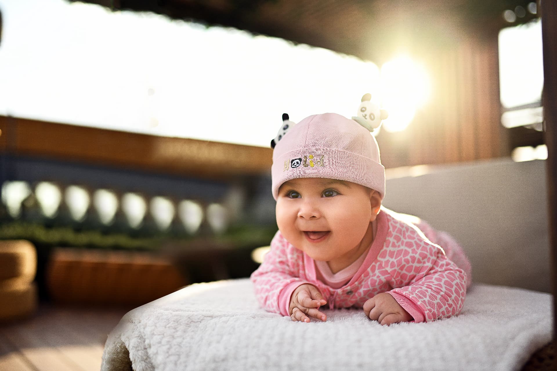 Baby in a pink hat smiling in warm backlight