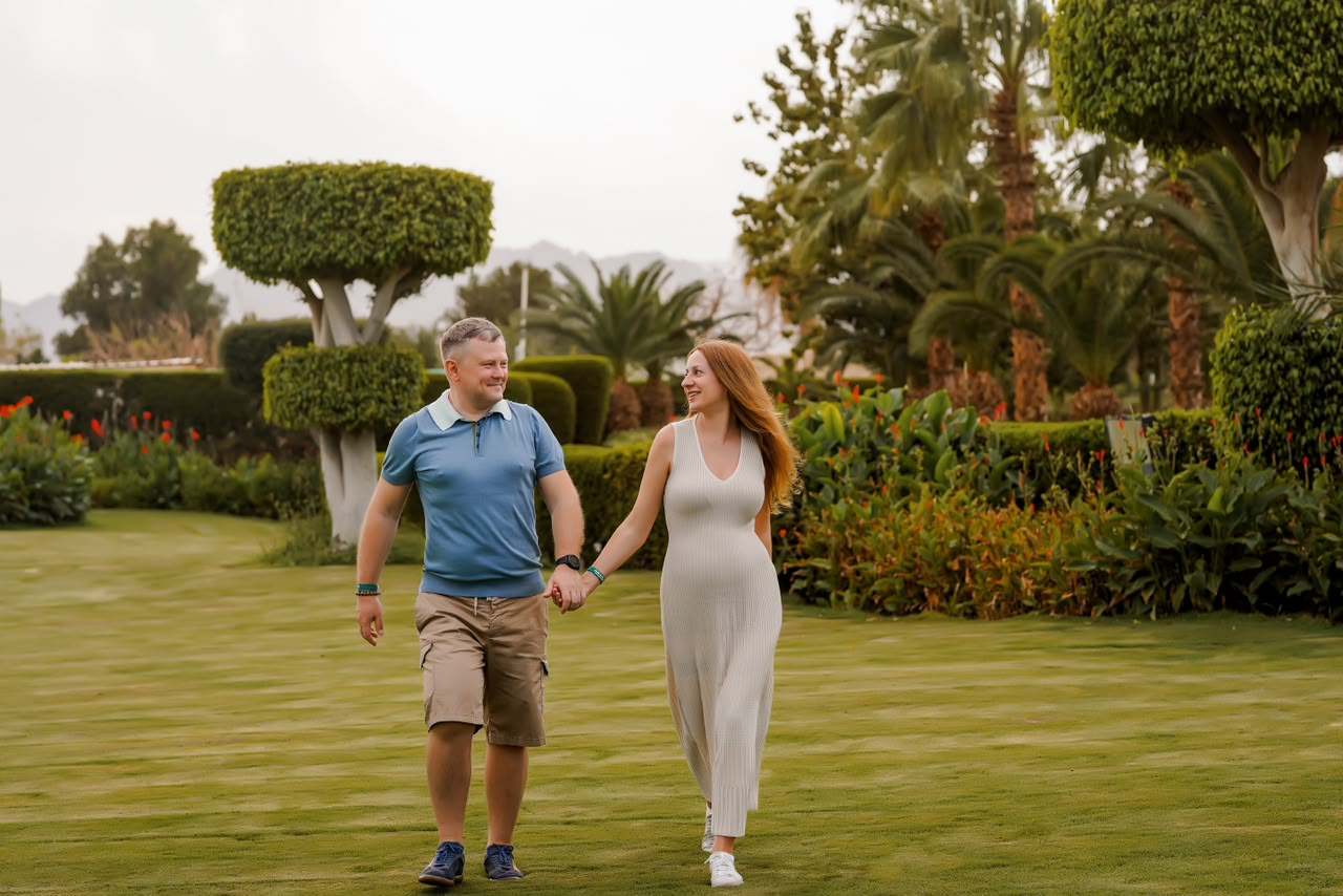 Couple walking hand in hand across a manicured garden lawn