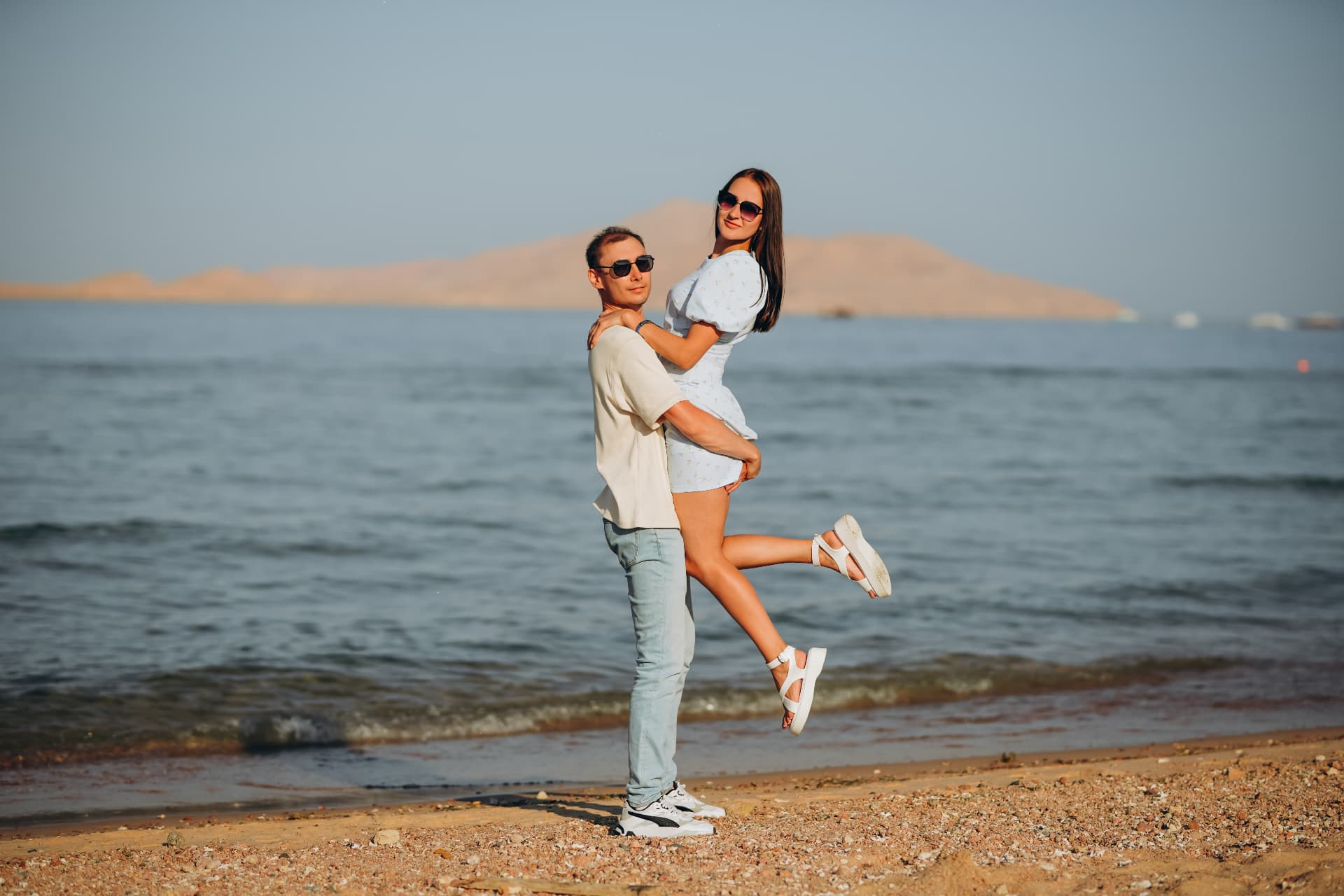 Couple embracing on a Red Sea beach with desert mountains behind them