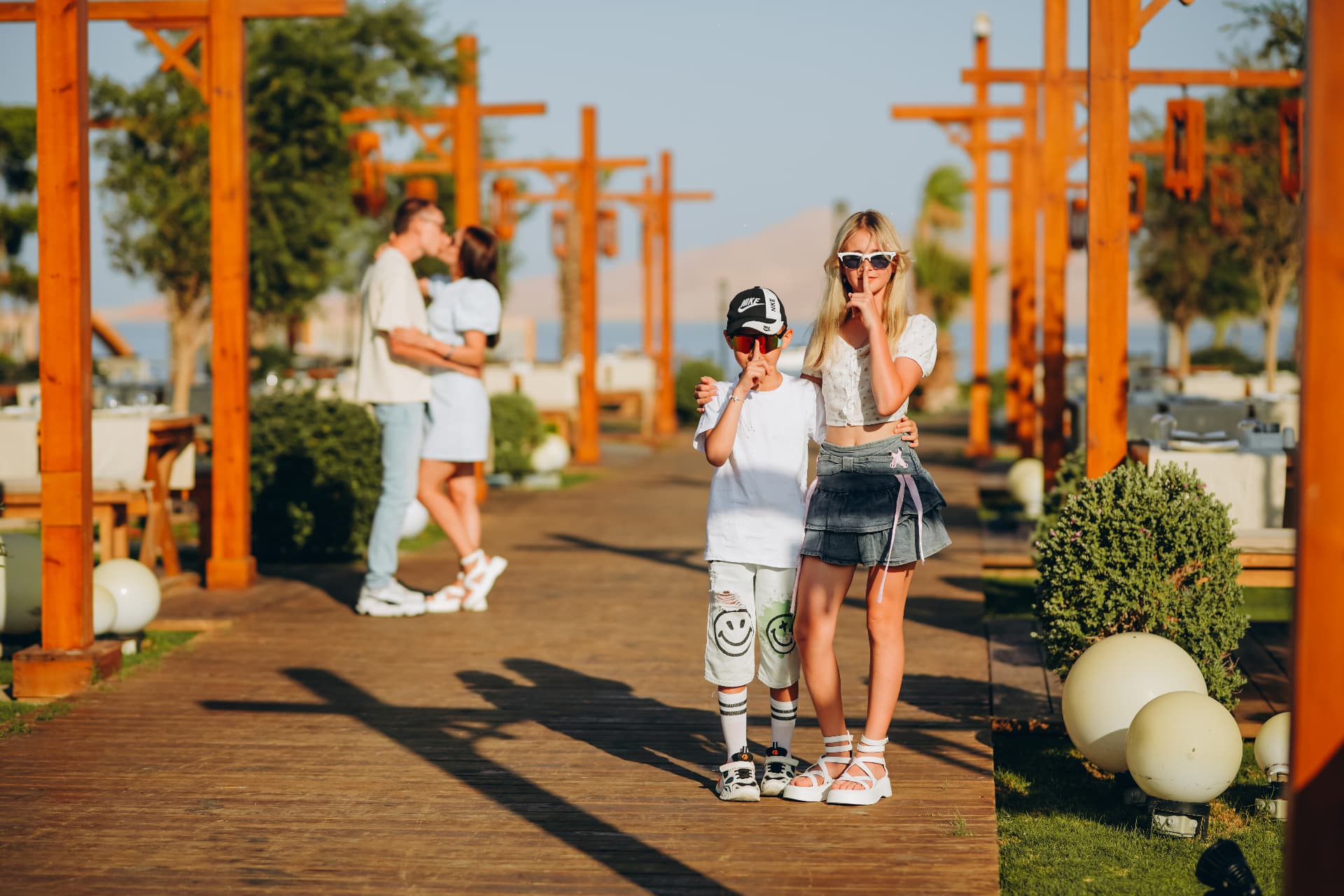 Brother and sister on a wooden walkway with their parents behind them