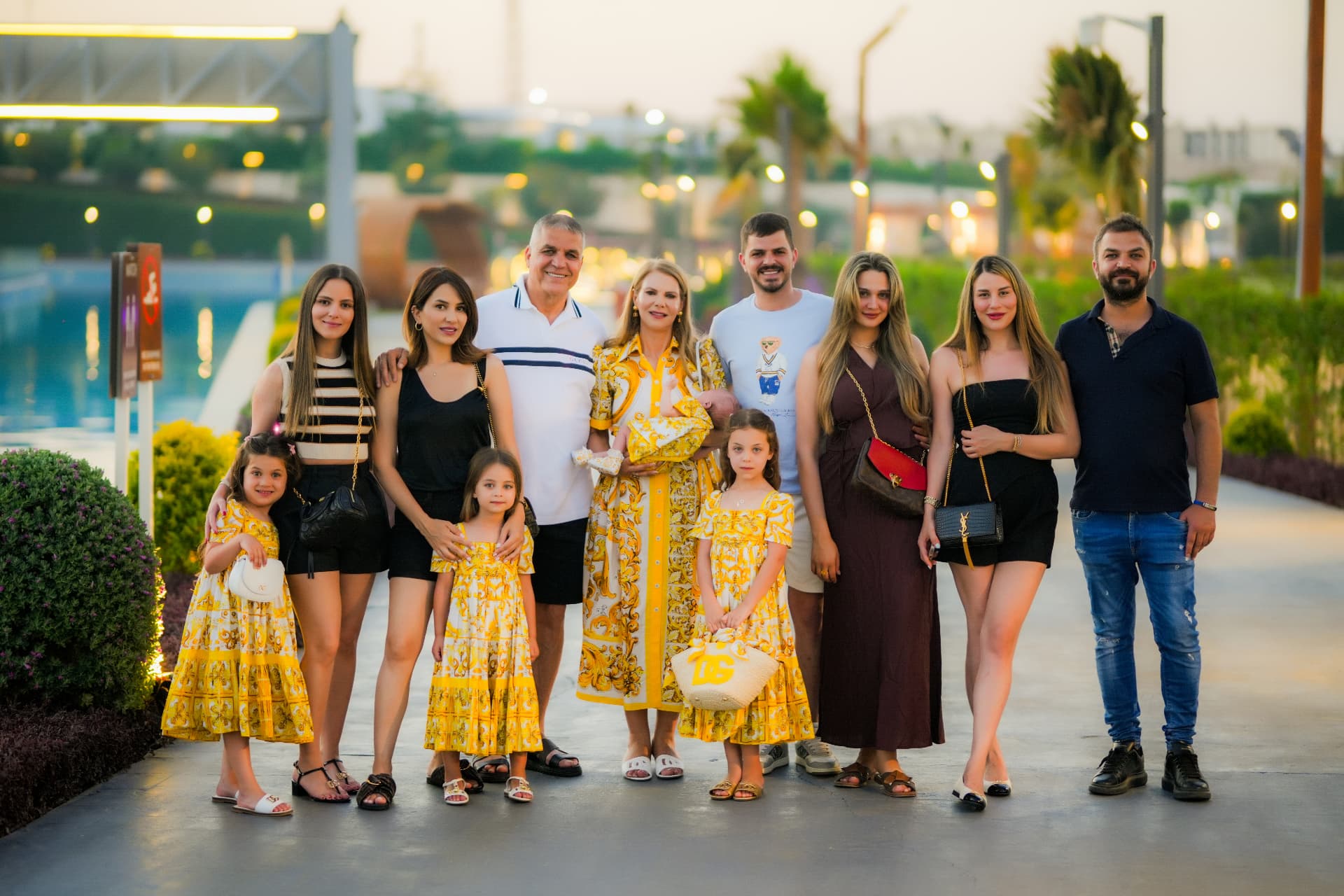 Large extended family portrait beside a resort pool at sunset