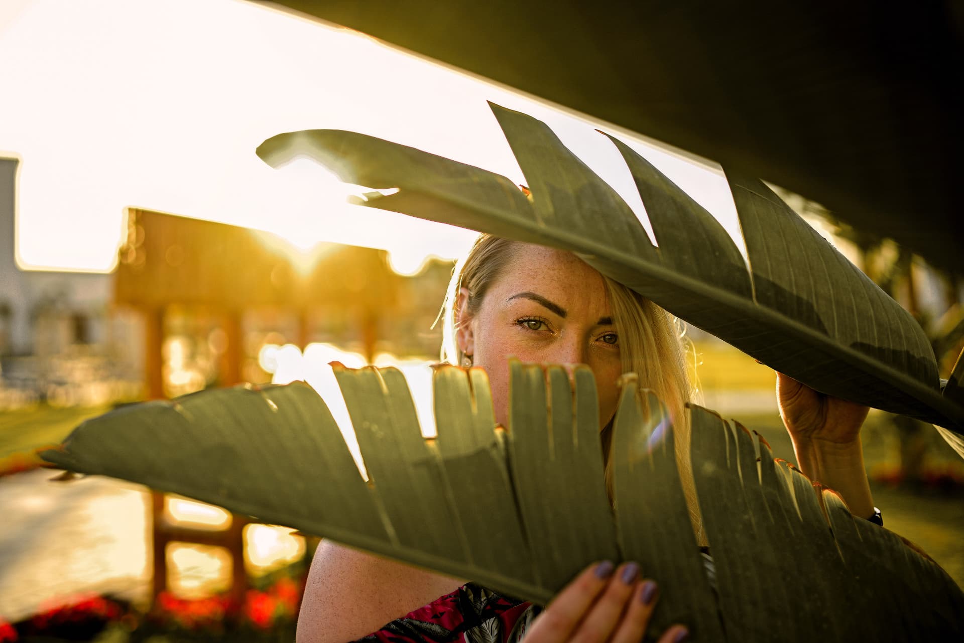 Woman framed by large tropical leaves in golden sunset light