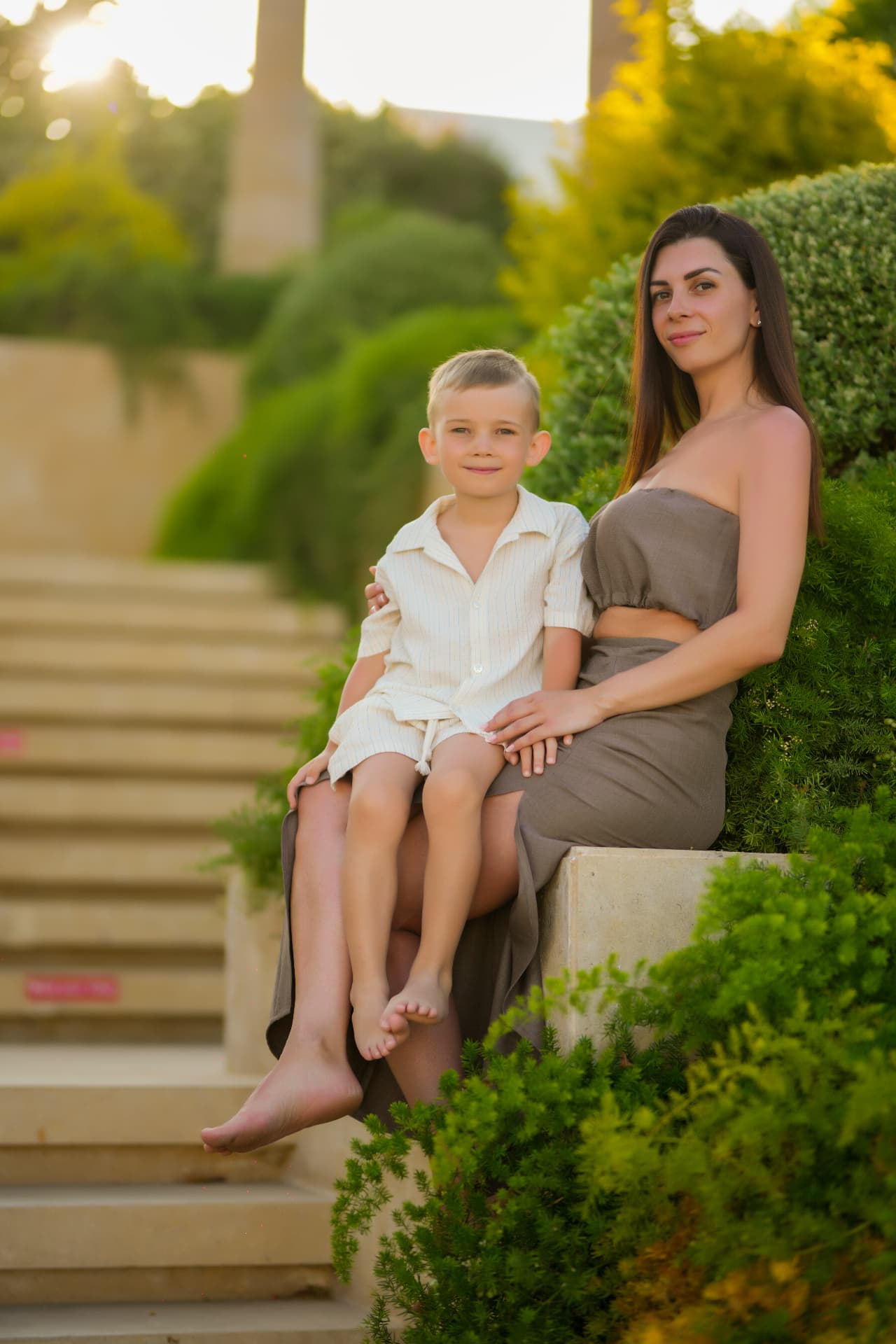 Mother and son seated on stone steps at sunset