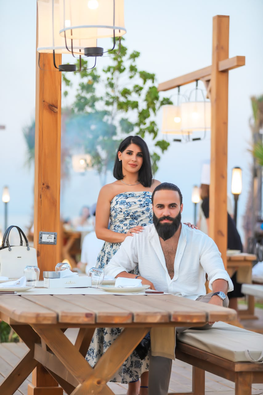 Couple at a wooden table at a beachside restaurant in the evening