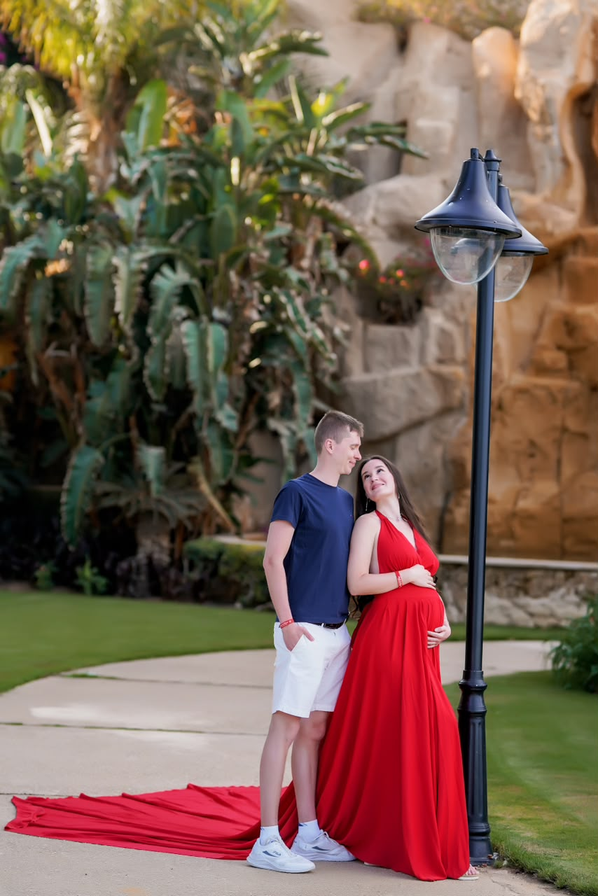 Couple on a garden path beneath a lamp post, red gown trailing behind